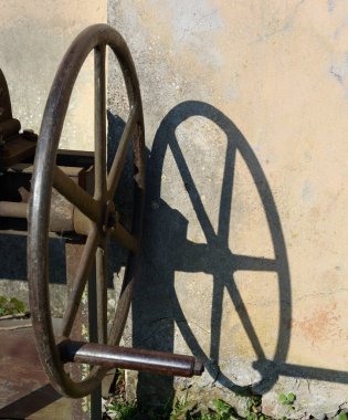 Duvarda gölgesi olan metal bir tekerlek..