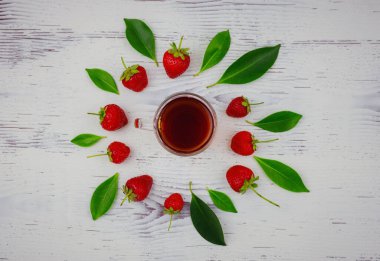 Taze organik çilekler ve cam fincanda siyah çay, beyaz arka planda. Vejetaryen sağlıklı gıda konsepti.