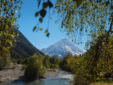 Irkis Vadisi 'nden, Arkhyz' den, Karachay-Cherkessia 'dan, Kuzey Kafkasya' dan. Mavi gökyüzü ve bulutlarıyla karlı dağ vadisi ve Kafkasya 'da Psysh nehrinin yakınında güzel bir orman. Alp manzarası.