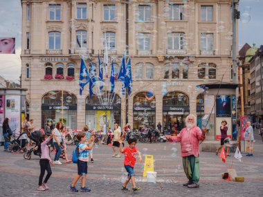 BASEL, SWitzERLAND, 7 Temmuz 2022: Adam baloncuklar üflüyor ve şehir merkezinde çocukları eğlendiriyor. Belediye binasının önündeki meydan.