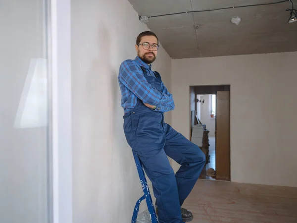 young man in blue work suit doing Repair apartment. Home renovation concept.