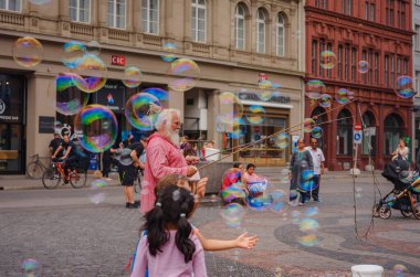 BASEL, SWitzERLAND, 7 Temmuz 2022: Adam baloncuklar üflüyor ve şehir merkezinde çocukları eğlendiriyor. Belediye binasının önündeki meydan.