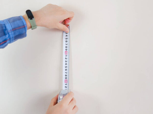 young man in blue work suit holding measure tape isolated on white background. Instruments, accessories, tools for renovation apartment room, selective focus