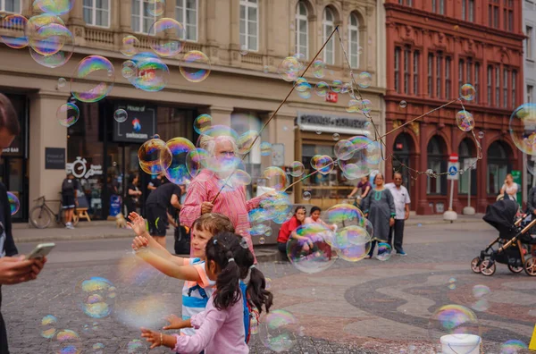 Stock image BASEL, SWITZERLAND, JULY 7, 2022: man blows bubbles and entertains kids in the city center. square in front of city hall