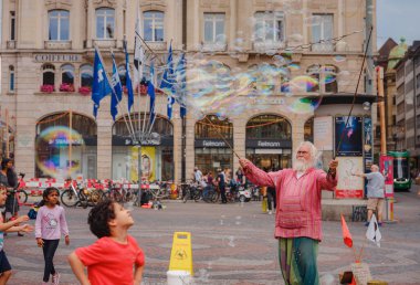 BASEL, SWitzERLAND, 7 Temmuz 2022: Adam baloncuklar üflüyor ve şehir merkezinde çocukları eğlendiriyor. Belediye binasının önündeki meydan.
