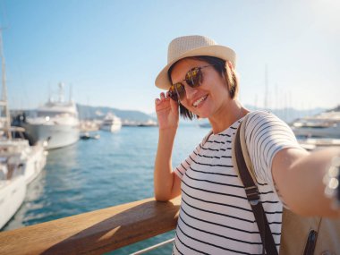 Marmaris, Türk Rivierası 'nın Turkuaz Sahili' ndeki tatil beldesi. Marmaris denize açılmak ve dalmak için harika bir yer. İskelede yürüyen şapkalı Asyalı kadın..