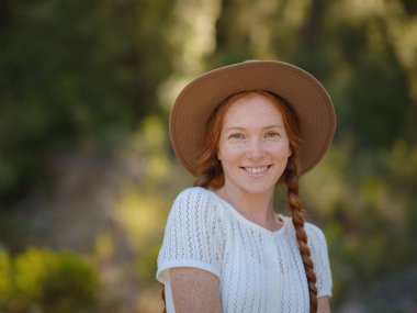 Beyaz, kızıl, genç, güzel, sırt çantalı, ormanda tek başına seyahat eden bir kadın. Çekici gezgin, tatil gezisi sırasında doğa ormanında mutluluk ve eğlenceyle yürürken etrafına bakar ve keşfederdi..