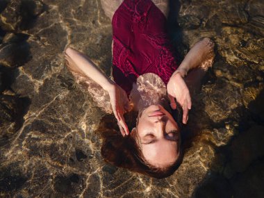 Kemer Antalya ilinin Phaselis kenti yakınlarındaki plajda dinlenen mayo giyen bayan turist. Eski Roma hamamlarının, tiyatroların, su kemerlerinin kalıntıları ve plajları olan antik bir liman şehri.