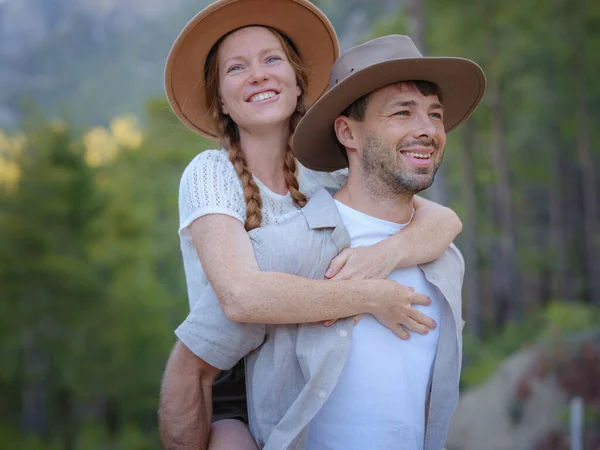 Young excited couple two friends family man woman in casual clothes boyfriend give piggyback ride to joyful girlfriend sit on back in summer day. Mountains Forest walk in Turkey