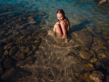 Kemer Antalya ilinin Phaselis kenti yakınlarındaki plajda dinlenen mayo giyen bayan turist. Eski Roma hamamlarının, tiyatroların, su kemerlerinin kalıntıları ve plajları olan antik bir liman şehri.