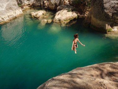 Sıcak bir yaz gününde Türkiye seyahati, Akdeniz bölgesi. Mayolu genç bir kadın dağ nehrinde eğleniyor. Açık hava, seyahat, aktif yaşam tarzı, yaz tatili kavramı.