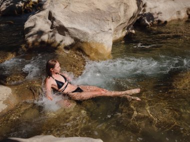 Sıcak bir yaz gününde Türkiye seyahati, Akdeniz bölgesi. Mayolu genç bir kadın dağ nehrinde eğleniyor. Açık hava, seyahat, aktif yaşam tarzı, yaz tatili, Friluftsliv