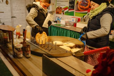 Düsselldorf, Almanya - 13 Aralık 2022: Kadınlar, petrolde kızartılmış geleneksel bir Macar ekmeği olan langosh 'u hazırlıyorlar. Noel pazarında yemek hazırlığı