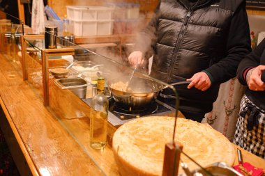 Düsselldorf, Almanya - 13 Aralık 2022: Adil Noel pazarında peynirli makarna pişirmek. Festivalde yemek hazırlığı