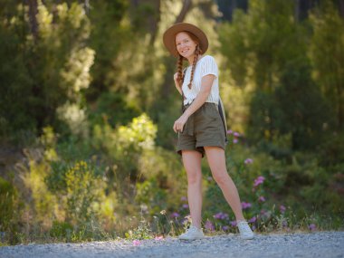 Beyaz, kızıl, genç, güzel, sırt çantalı, ormanda tek başına seyahat eden bir kadın. Çekici gezgin, tatil gezisi sırasında doğa ormanında mutluluk ve eğlenceyle yürürken etrafına bakar ve keşfederdi..