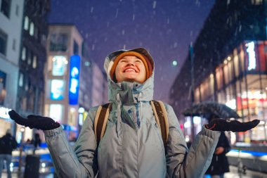 snowfall woman in a blue jacket and yellow hat christmas outside, city portrait in snowfall, young model posing in Dusseldorf city, fabulous advent evening