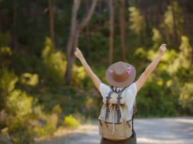 Beyaz, kızıl, genç, güzel, sırt çantalı, ormanda tek başına seyahat eden bir kadın. Çekici gezgin, tatil gezisi sırasında doğa ormanında mutluluk ve eğlenceyle yürürken etrafına bakar ve keşfederdi..