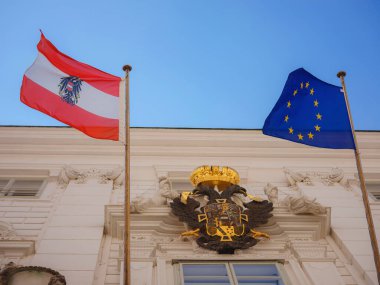 Ancient building with the flag of Austria and the European Union and the coat of arms of Austria. Summer Travel to capital of Austria Vienna.