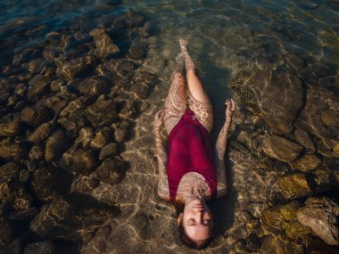 Kemer Antalya ilinin Phaselis kenti yakınlarındaki plajda dinlenen mayo giyen bayan turist. Eski Roma hamamlarının, tiyatroların, su kemerlerinin kalıntıları ve plajları olan antik bir liman şehri.