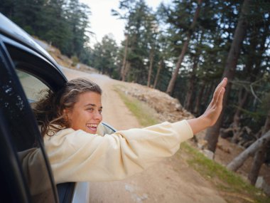 Woman on road trip traveling by rental car . adventure lifestyle vacations vibes outdoor sunset Turkey mountains forest, Fethie , Babadag mount. Happy female raising her hand out of the car window.