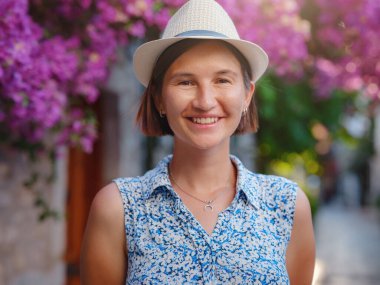 Blooming bougainvillea, streets of the old town of Bodrum, Turkey. Happy traveler woman in white elegant outfit walking by romantic streets . Summer travelling