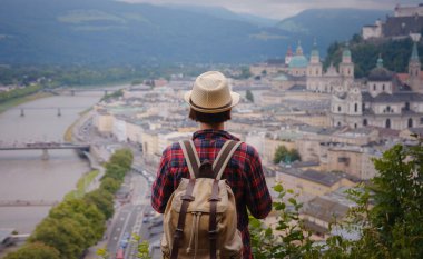 summer female solo trip to Europe, happy young woman walking over Salzburg, trail with viewponts on the old town. Austria summer travel
