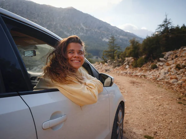 Woman on road trip traveling by rental car . adventure lifestyle vacations vibes outdoor sunset Turkey mountains forest, Fethie , Babadag mount. Happy female raising her hand out of the car window.