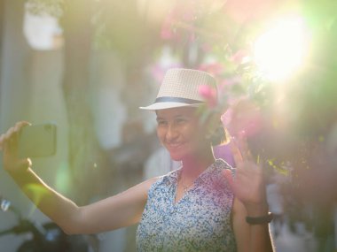 Çiçekli begonviller, eski Bodrum kasabasının sokakları, Türkiye. Romantik caddelerde yürüyen beyaz şık elbiseli mutlu bir gezgin kadın. Yaz gezisi