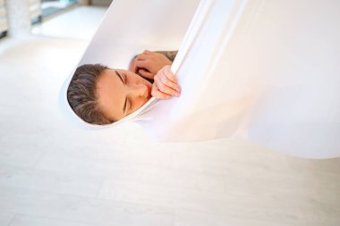 workshop of air yoga and stretching in yoga studio. woman meditating after class of antigravity yoga with hammock. balance between mental and physical, one person effort and achievement concept