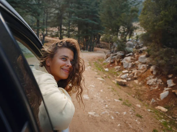 Woman on road trip traveling by rental car . adventure lifestyle vacations vibes outdoor sunset Turkey mountains forest, Fethie , Babadag mount. Happy female raising her hand out of the car window.