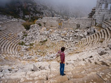 Sonbahar yürüyüşü, Türkiye 'nin Termessos Antik Kenti' ndeki antik amfitiyatroya bakan kadın. Türkiye 'nin en seçkin arkeolojik sahaları ve başlıca turizm merkezlerinden biri.