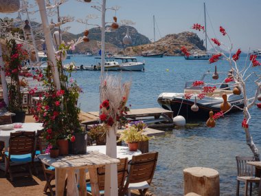 Bodrum 'dan Türkiye' ye yaz yolculuğu. Bodrum, Gumusluk Town 'daki Ege balık lokantası masası. Restoran masaları ve sandalyeler denizde.