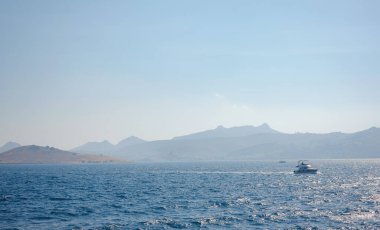 Bodrum 'dan Türkiye' ye yaz yolculuğu. Yaz öğlen deniz köyü Gumusluk Mugla ili, açık mavi su ve teknelerle körfez