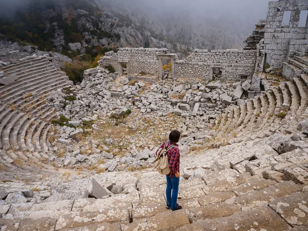 Autumn walk , woman looking at the ancient amphitheatre in city Termessos Ancient City, Turkey. Turkeys most outstanding archaeological sites and one of main tourist center.