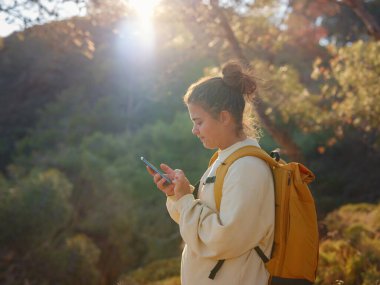 Seyahat ve aktif yaşam tarzı konsepti. Dağlarda yürüyüş yapan mutlu kadın, Fethie, Türkiye. Genç Yürüyüşçü akıllı telefon ve dijital iletişim kullanıyor. Sosyal ağda, açık havada arkadaşlarla mesajlaşmak