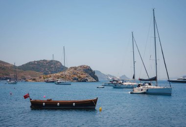 Bodrum 'dan Türkiye' ye yaz yolculuğu. Yaz öğlen deniz köyü Gumusluk Mugla ili, açık mavi su ve teknelerle körfez