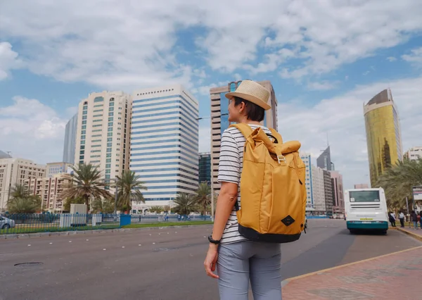 在阿布扎比市中心的街上 快乐的年轻亚洲女性带着背包和帽子旅行到了阿拉伯联合酋长国 度假和旅游目的地概念 — 图库照片