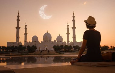 Birleşik Arap Emirlikleri 'ne seyahat. Sırt çantalı ve şapkalı Asyalı mutlu genç bayan gezgin. Oasis of Reality ve Shaikh Zayed Büyük Camii' nde. Ay silueti, ramazan bayramı konsepti
