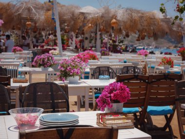 Bodrum 'dan Türkiye' ye yaz yolculuğu. Bodrum, Gumusluk Town 'daki Ege balık lokantası masası. Restoran masaları ve sandalyeler denizde.