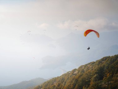 Paragliding in sky. Paraglider tandem flying over sea and mountains in cloudy day. view of paraglider and Blue Lagoon in Oludeniz, Turkey. Extreme sport. Landscape
