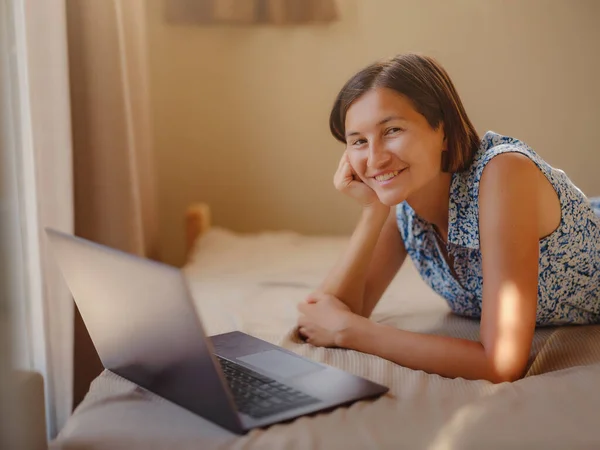 Happy young asian woman with laptop resting in bedroom in tiny house, weekend away and remote office idea. Tiny houses and Small Living concept.