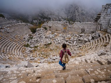 Sonbahar yürüyüşü, Türkiye 'nin Termessos Antik Kenti' ndeki antik amfitiyatroya bakan kadın. Türkiye 'nin en seçkin arkeolojik sahaları ve başlıca turizm merkezlerinden biri.