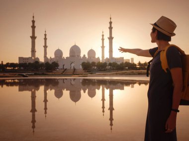 Birleşik Arap Emirlikleri 'ne seyahat, Wahat Al Karama ya da Haysiyet Vahası' nda sırt çantası ve şapkası olan mutlu Asyalı genç bayan gezgin şehitleri için kalıcı anıt ve Shaikh Zayed Büyük Camii..