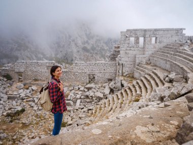 Sonbahar yürüyüşü, Türkiye 'nin Termessos Antik Kenti' ndeki antik amfitiyatroya bakan kadın. Türkiye 'nin en seçkin arkeolojik sahaları ve başlıca turizm merkezlerinden biri.