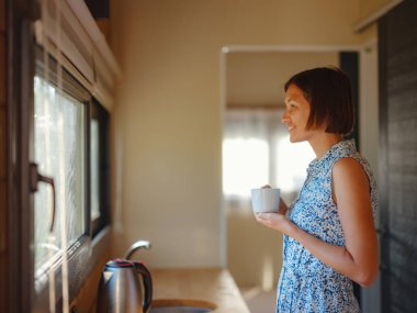 Genç bir kadın sabah mutfağında kahvesini yudumluyor. Minimalizm. İçeri giriyoruz. Yalnız yaşamak. Büyüleyici karavan evi.