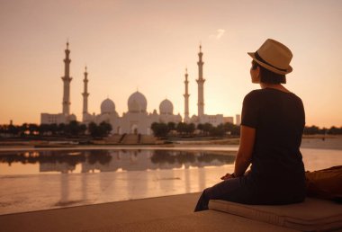 Birleşik Arap Emirlikleri 'ne seyahat, Wahat Al Karama ya da Haysiyet Vahası' nda sırt çantası ve şapkası olan mutlu Asyalı genç bayan gezgin şehitleri için kalıcı anıt ve Shaikh Zayed Büyük Camii..