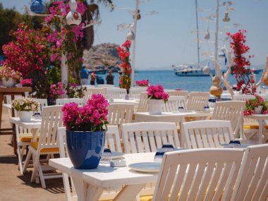 Bodrum 'dan Türkiye' ye yaz yolculuğu. Bodrum, Gumusluk Town 'daki Ege balık lokantası masası. Restoran masaları ve sandalyeler denizde.