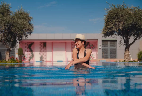 穿着黑色泳衣 头戴帽子 在游泳池温泉放松的美丽的亚洲女人的画像 炎炎夏日 阳光灿烂 旅游中的健康身体护理 — 图库照片