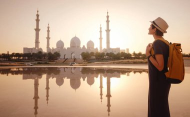 Birleşik Arap Emirlikleri 'ne seyahat, Wahat Al Karama ya da Haysiyet Vahası' nda sırt çantası ve şapkası olan mutlu Asyalı genç bayan gezgin şehitleri için kalıcı anıt ve Shaikh Zayed Büyük Camii..