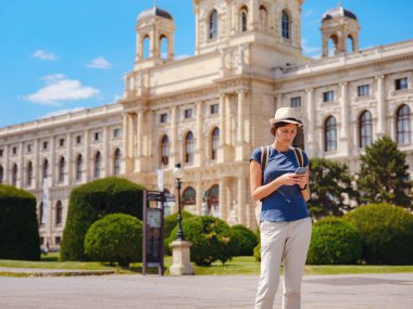 summer female solo trip to Europe, happy young woman walking on european street. Maria Theresa square near museum of Natural history in Vienna.